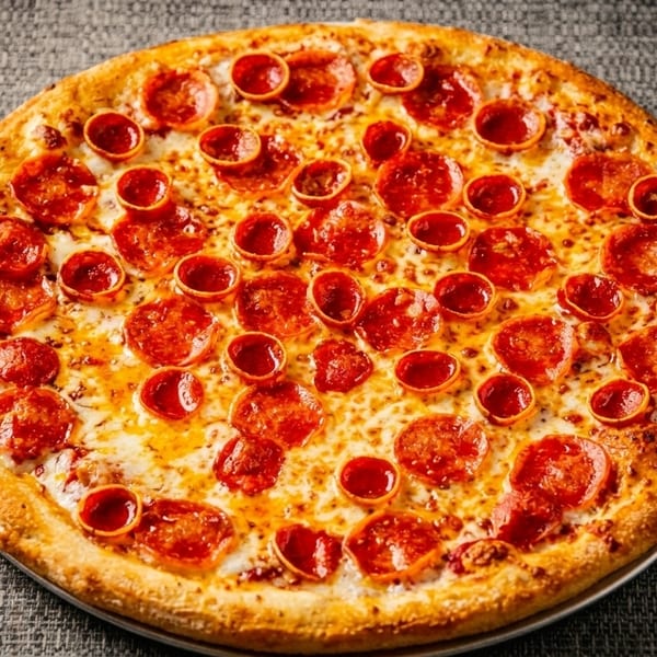 A whole pepperoni pizza with a golden crust and melted cheese on a dark gray textured surface.