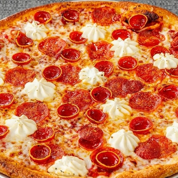 A large pepperoni pizza with dollops of white cheese, on a metal pan over a grey tablecloth.
